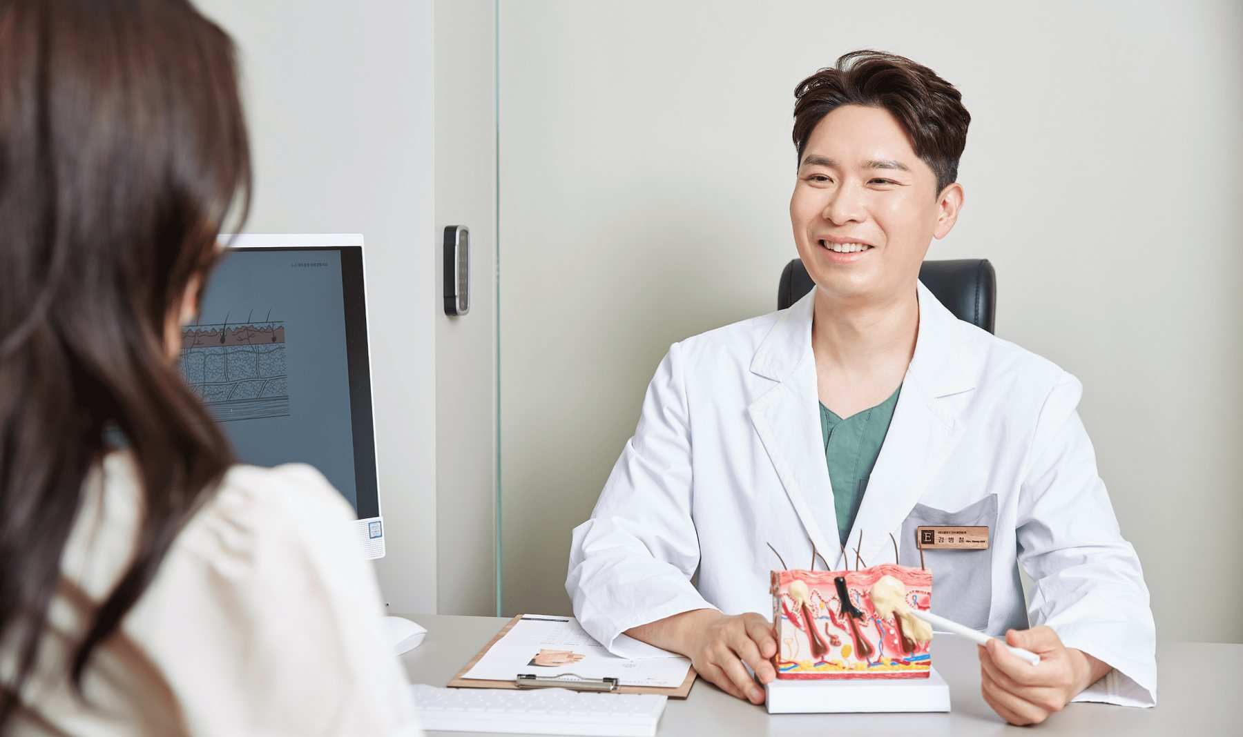 진료실에서 피부 모형을 들고 상담하는 김병철 대표원장