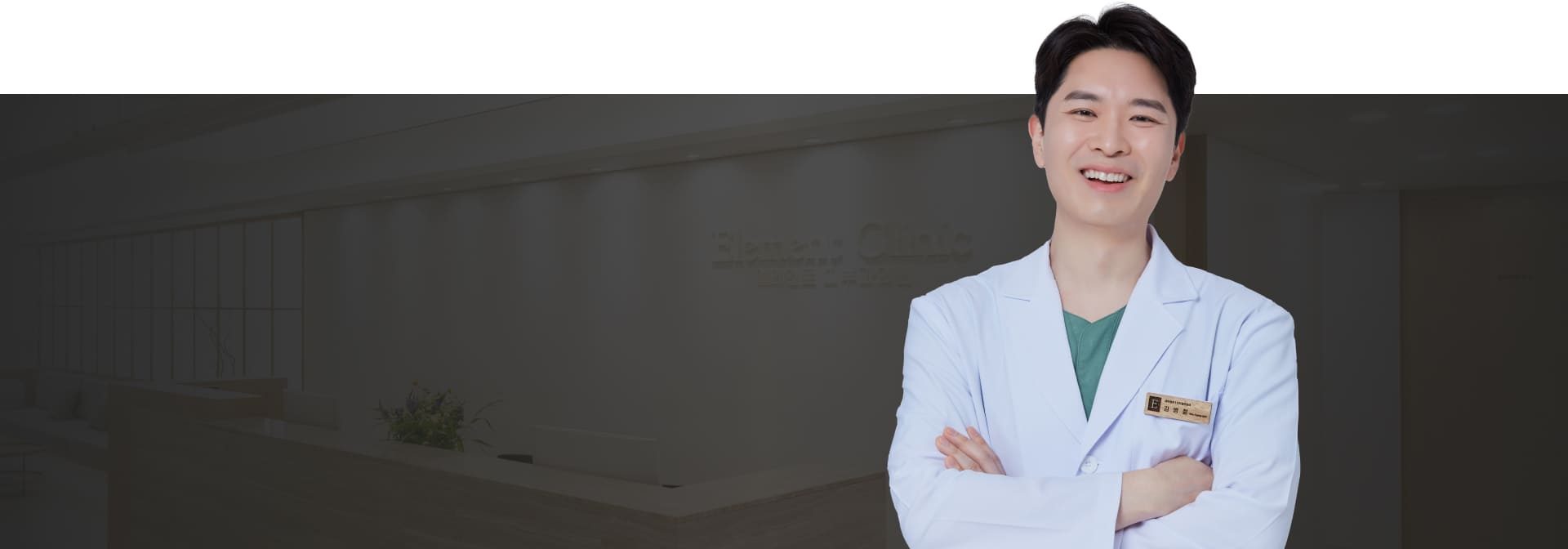 팔짱을 끼고 웃는 김병철 대표원장(어둡게 눌린 병원 접수 공간 배경)